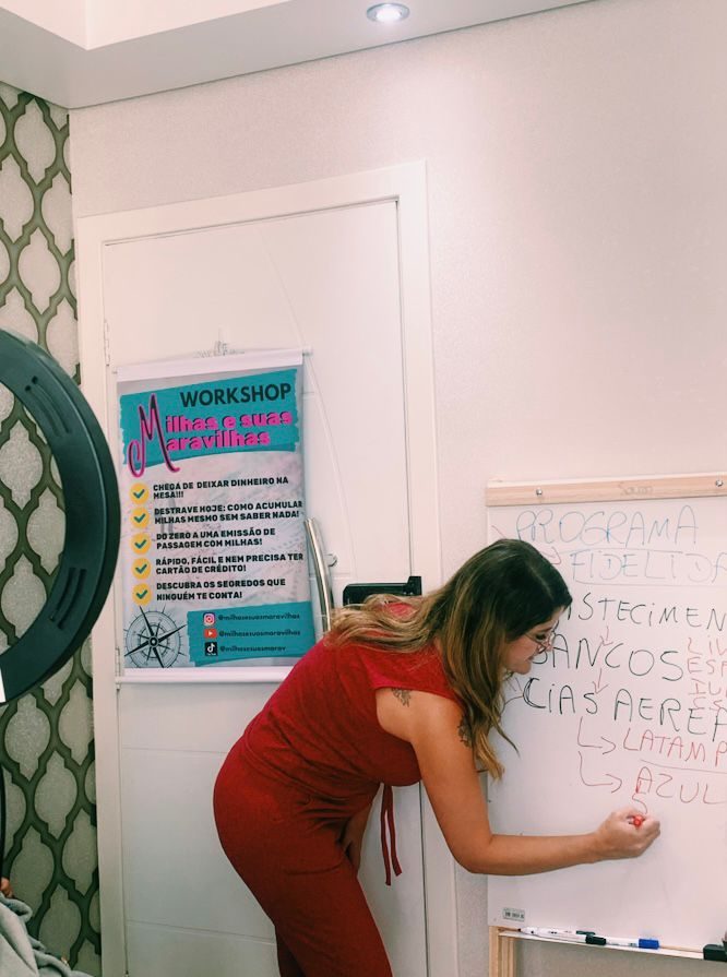 Alessandra ensinando milhas no quadro, durante o workshop